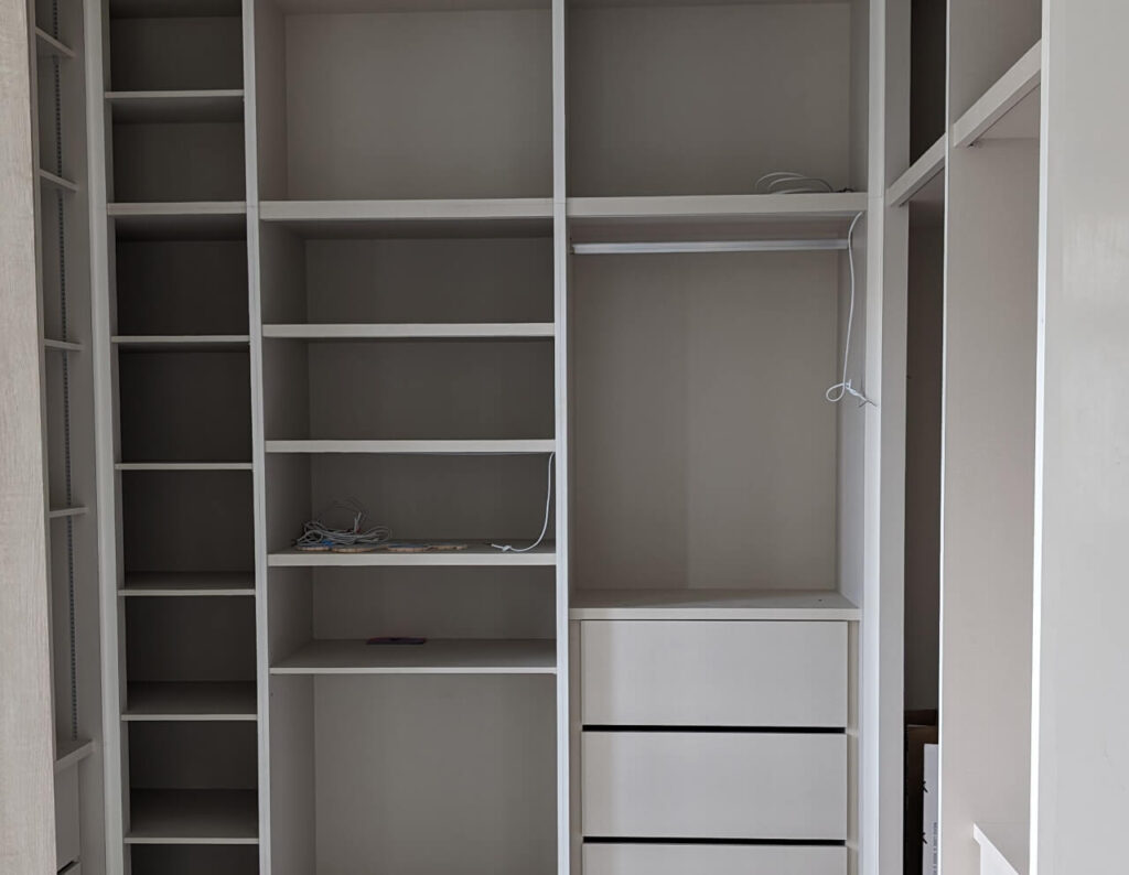 Custom-built wardrobe with shelves and drawers designed for space optimization in a minimalist room